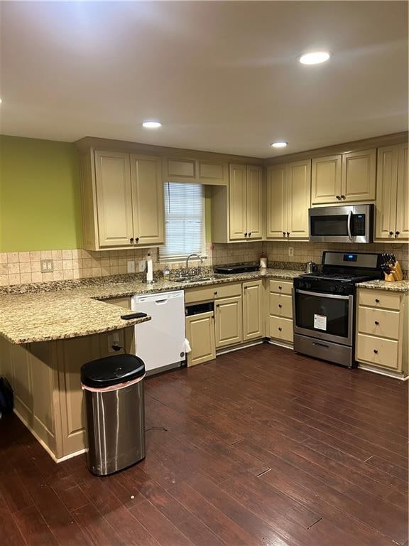 kitchen with stainless steel appliances, dark hardwood / wood-style floors, sink, and light stone countertops