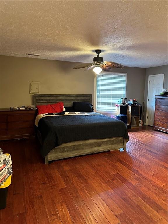 bedroom with ceiling fan, dark hardwood / wood-style floors, and a textured ceiling