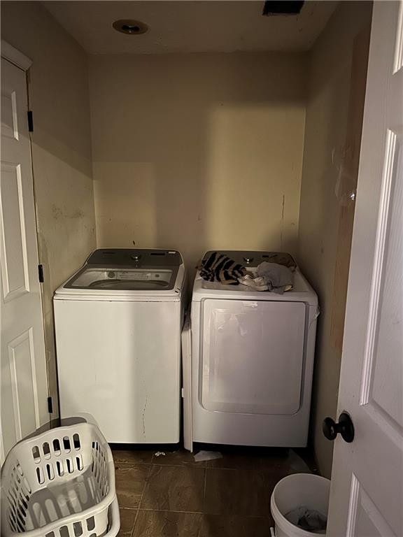 laundry area with washing machine and dryer and dark tile patterned floors