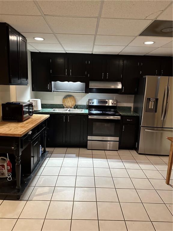 kitchen with a paneled ceiling, light tile patterned floors, and stainless steel appliances