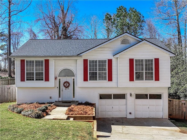 split foyer home with a shingled roof, fence, concrete driveway, a front yard, and a garage