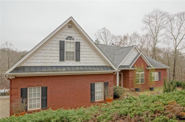 view of side of property featuring a standing seam roof, brick siding, and metal roof