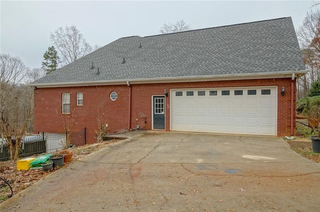 exterior space with concrete driveway, brick siding, fence, and an attached garage