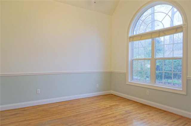 unfurnished room with light wood-type flooring, baseboards, and lofted ceiling