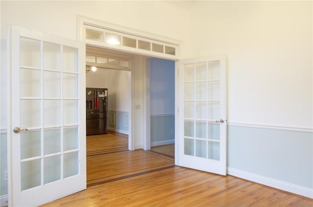 empty room featuring baseboards, wood finished floors, and french doors