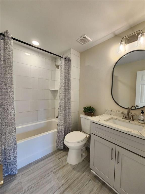 full bathroom featuring shower / bathtub combination with curtain, vanity, and toilet