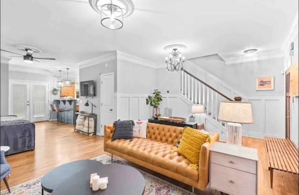 living room with crown molding, light hardwood / wood-style floors, and ceiling fan with notable chandelier