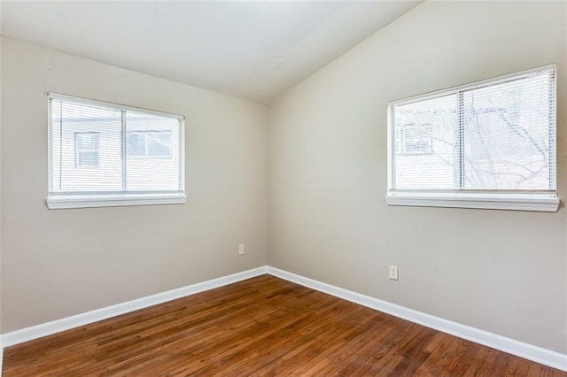 empty room with hardwood / wood-style flooring and lofted ceiling