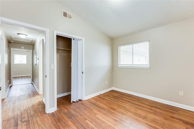 unfurnished bedroom with lofted ceiling, hardwood / wood-style flooring, and a closet