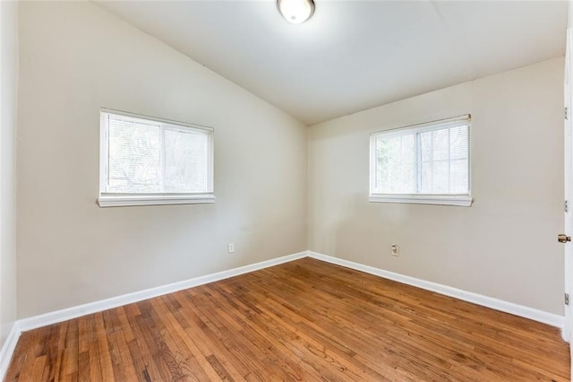 empty room featuring wood-type flooring, vaulted ceiling, and plenty of natural light