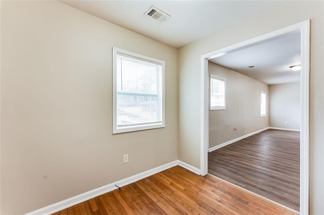 empty room with plenty of natural light and light hardwood / wood-style floors