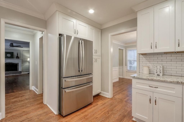 kitchen with white cabinetry, light stone countertops, stainless steel fridge, and crown molding