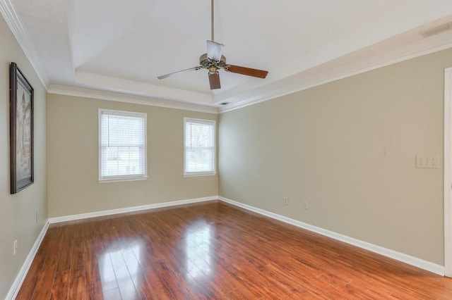 empty room with hardwood / wood-style flooring, ceiling fan, a tray ceiling, and crown molding