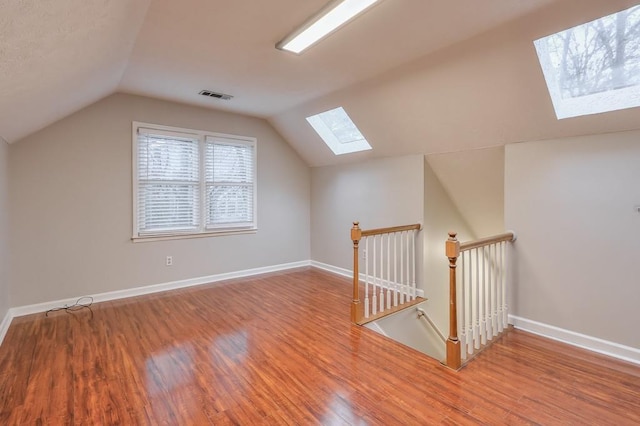 additional living space featuring hardwood / wood-style floors and vaulted ceiling with skylight