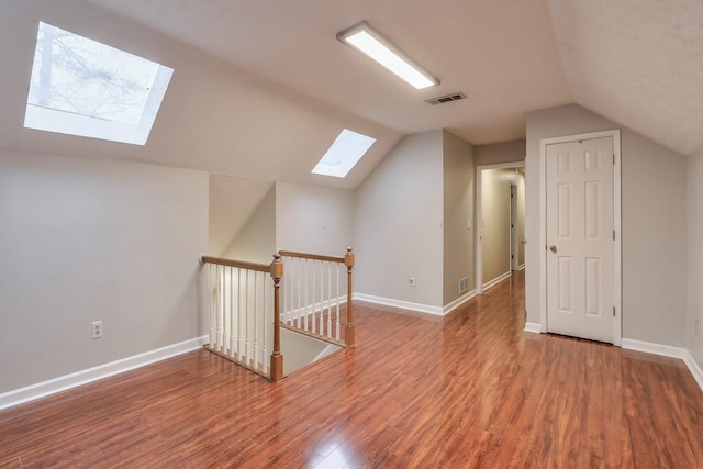 bonus room with wood-type flooring and vaulted ceiling with skylight