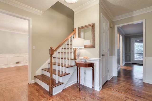 staircase with hardwood / wood-style flooring and crown molding