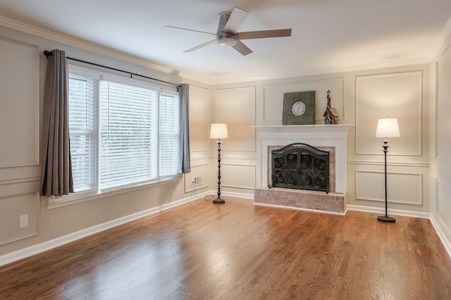 unfurnished living room with hardwood / wood-style flooring, ceiling fan, ornamental molding, and a fireplace