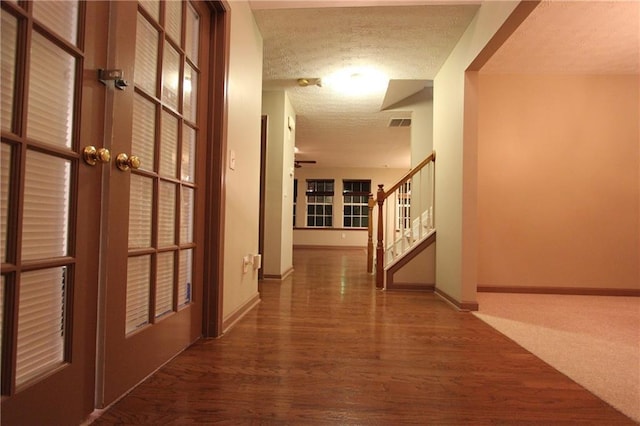 corridor with visible vents, baseboards, wood finished floors, stairs, and a textured ceiling