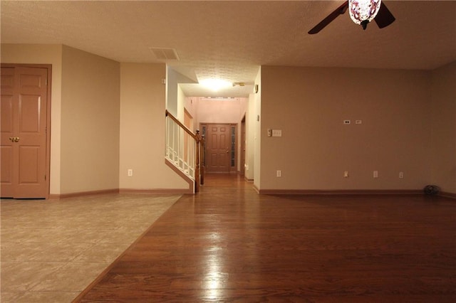 spare room with visible vents, stairway, baseboards, and wood finished floors