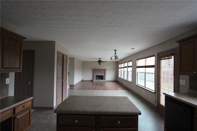 kitchen with baseboards, open floor plan, a center island, a textured ceiling, and a fireplace