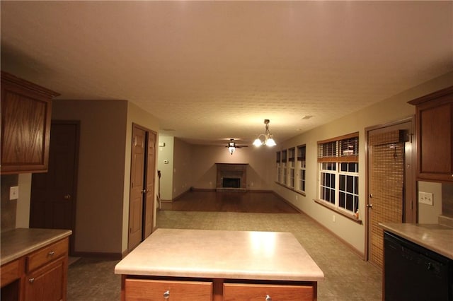 kitchen with brown cabinetry, a fireplace with raised hearth, dishwasher, and light countertops