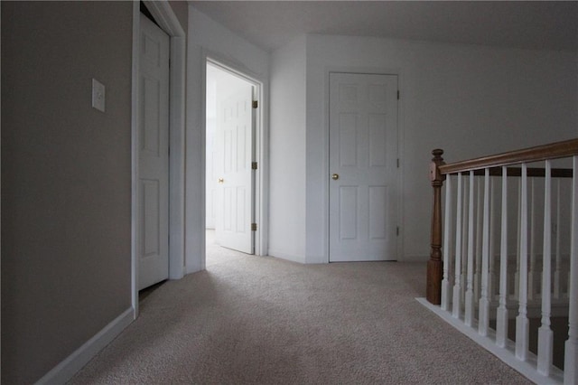 hall with light colored carpet and baseboards