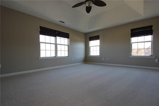 carpeted spare room with a ceiling fan, a tray ceiling, visible vents, and baseboards