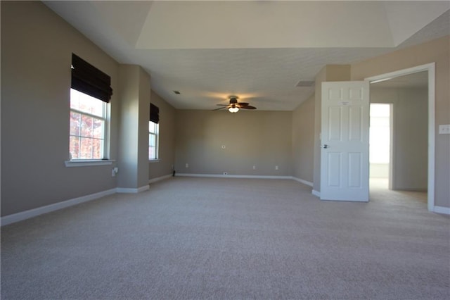 spare room with a ceiling fan, light colored carpet, visible vents, and baseboards