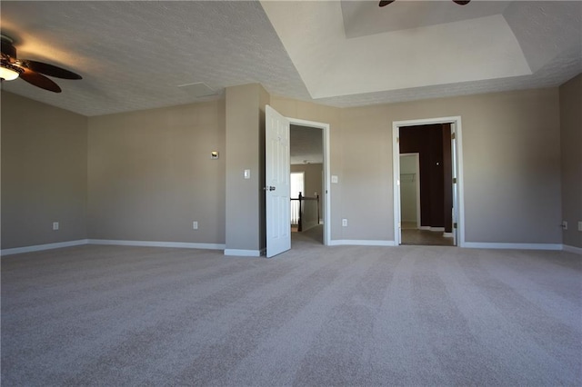 carpeted empty room with a raised ceiling, ceiling fan, a textured ceiling, and baseboards