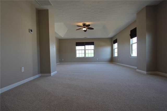 empty room featuring ceiling fan, light carpet, visible vents, baseboards, and a raised ceiling