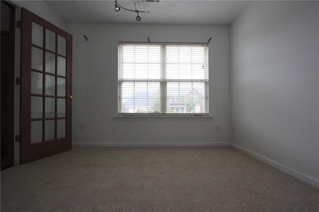 carpeted spare room with plenty of natural light and baseboards