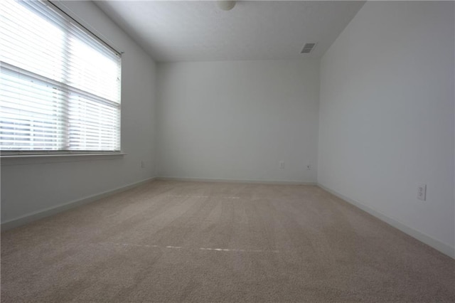 empty room featuring baseboards, visible vents, and light colored carpet