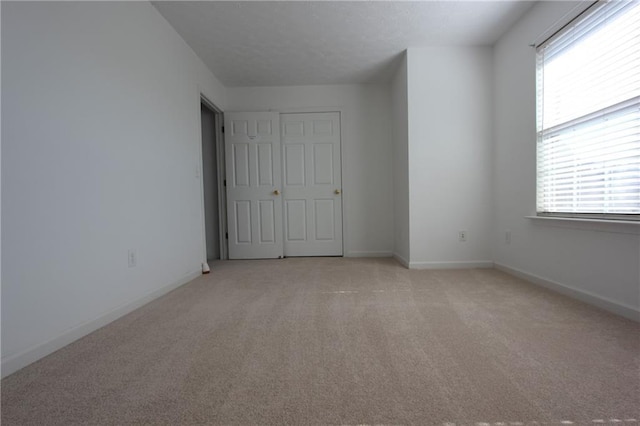 unfurnished bedroom with light carpet and baseboards