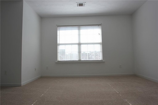 carpeted empty room with a textured ceiling, visible vents, and baseboards