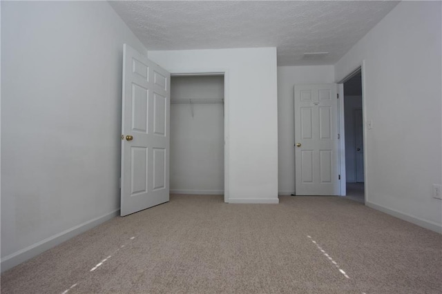 unfurnished bedroom with carpet, a closet, baseboards, and a textured ceiling