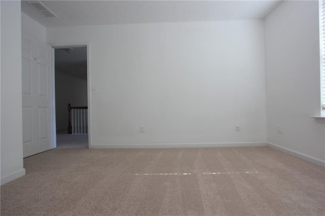 carpeted spare room with visible vents and baseboards