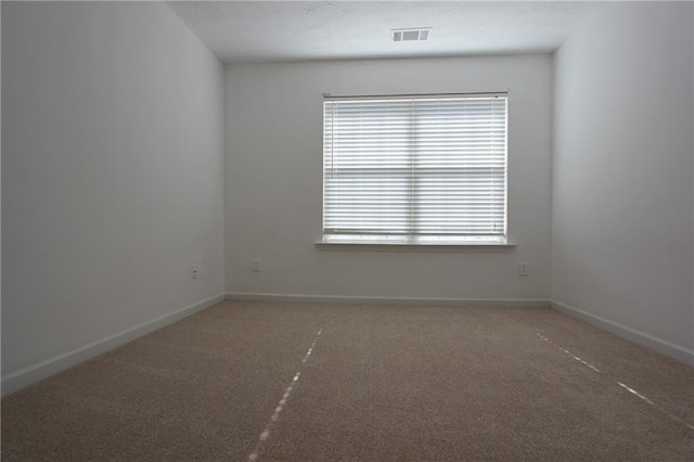 carpeted spare room featuring visible vents and baseboards