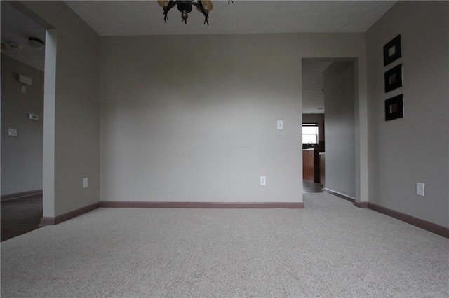 spare room with baseboards and light colored carpet