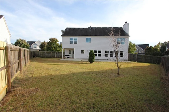 rear view of property featuring a patio area, a fenced backyard, a chimney, and a yard