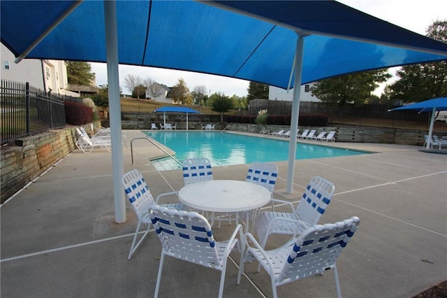 pool with outdoor dining space, fence, and a patio