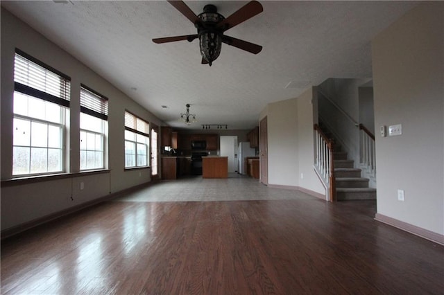 unfurnished living room featuring light wood-style floors, baseboards, stairway, and a textured ceiling