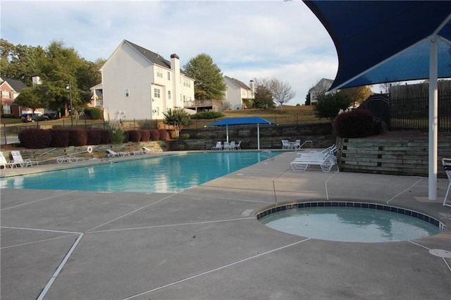 community pool featuring a patio area, a hot tub, and fence