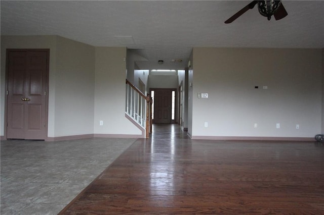 unfurnished living room featuring ceiling fan, stairway, baseboards, and wood finished floors