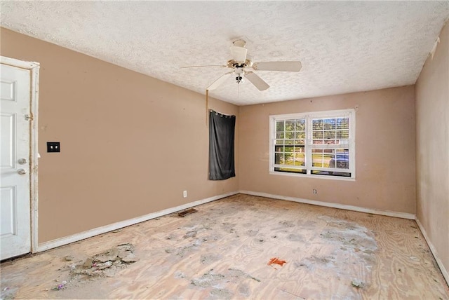 unfurnished room featuring a textured ceiling, ceiling fan, and baseboards