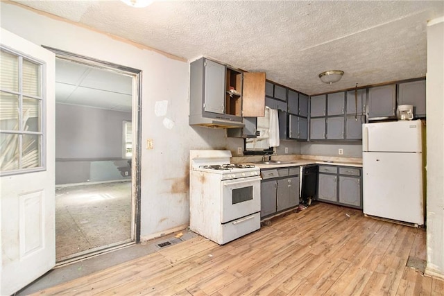 kitchen featuring white appliances, gray cabinetry, a sink, light wood-style flooring, and a textured ceiling