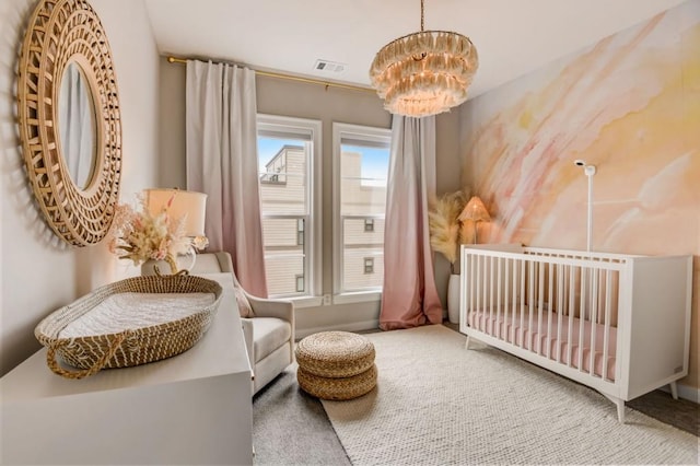 carpeted bedroom featuring a crib and a chandelier