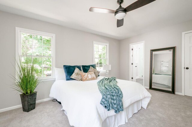 bedroom featuring light carpet, ceiling fan, and baseboards