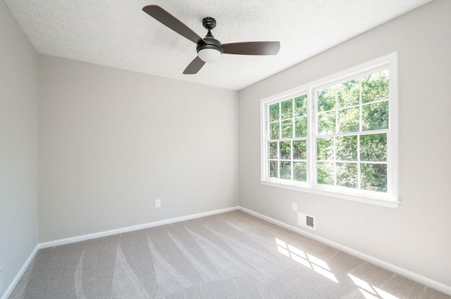 carpeted spare room with a ceiling fan, visible vents, a textured ceiling, and baseboards