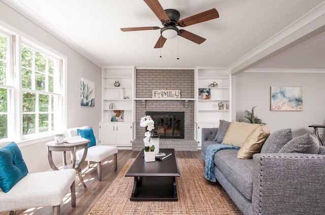 living room with ornamental molding, a fireplace, built in features, and wood finished floors