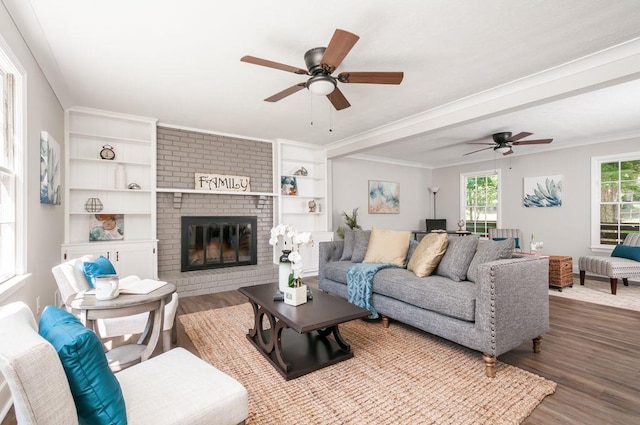 living room with ceiling fan, a fireplace, wood finished floors, and crown molding